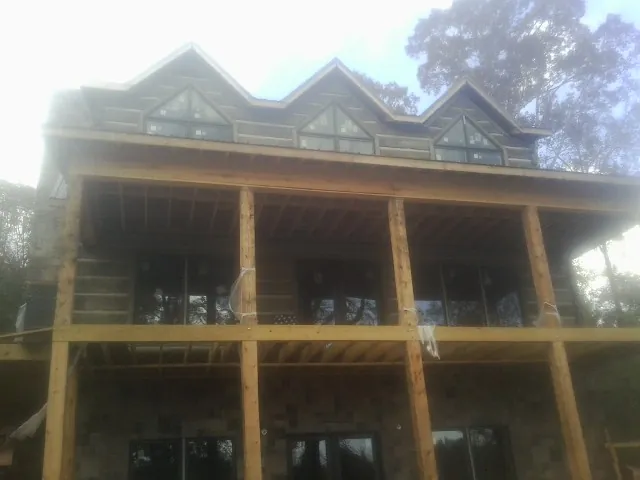 Dormers and porch framing on a large log home under construction — Roof Coating work by our crew in Tar Heel