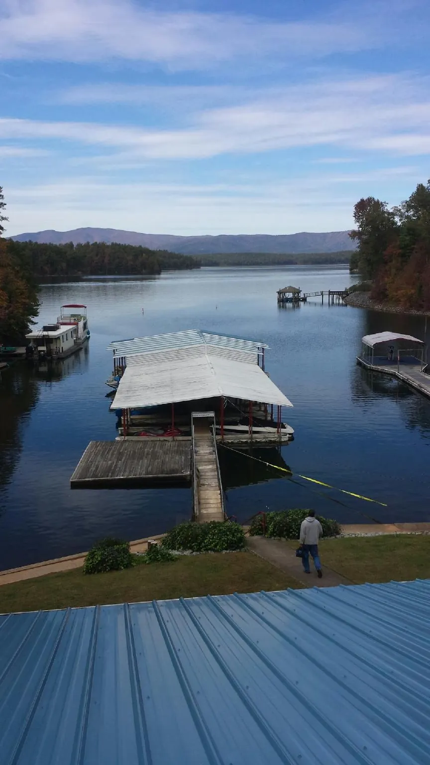 View across a lake from a newly installed blue metal roof in Tar Heel