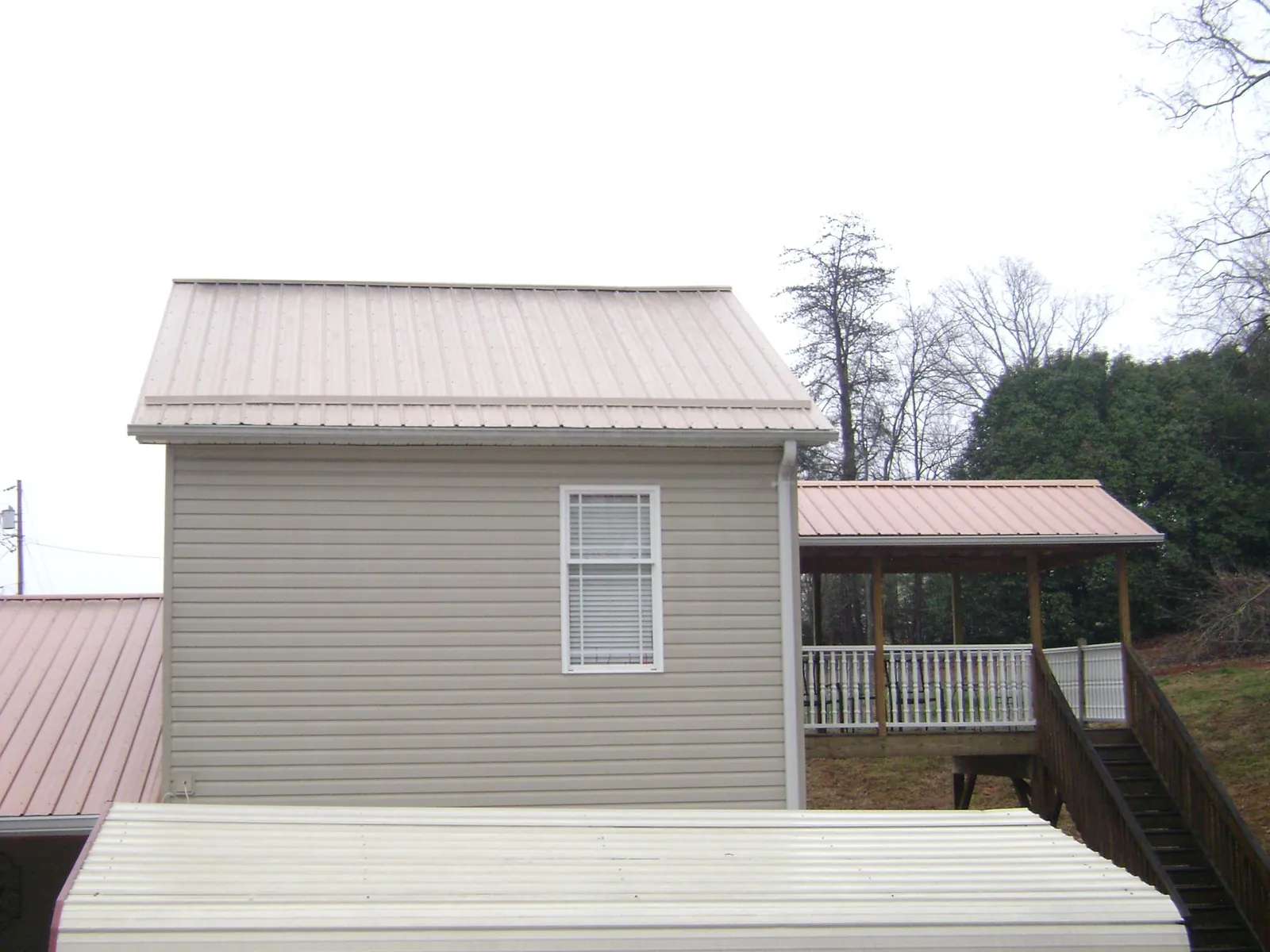 Tan metal roofs on a two story addition and attached porch, from a Roof Replacement job in Tar Heel